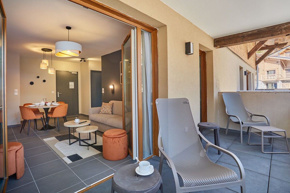 A modern living room with a sofa, coffee table, and chairs, a dining area with a table and chairs, and a balcony with seating.
