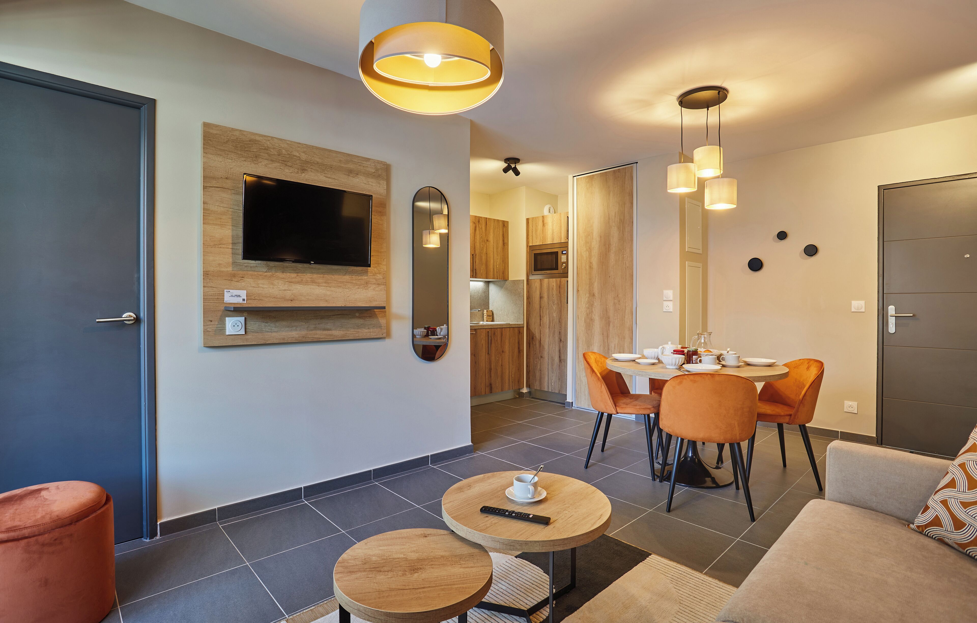 A modern living room with a TV mounted on the wall, a dining area with a table and chairs, and a sofa.
