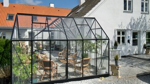 A greenhouse with a glass roof, wicker furniture, and potted plants. - Marielyst Sleep and Go (Vaeggerlose)