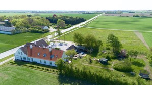 A large white building with a red roof, surrounded by green fields and trees. - Marielyst Sleep and Go (Vaeggerlose)