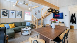 Una sala moderna con un sofá verde, una mesa de comedor de madera y una escalera.