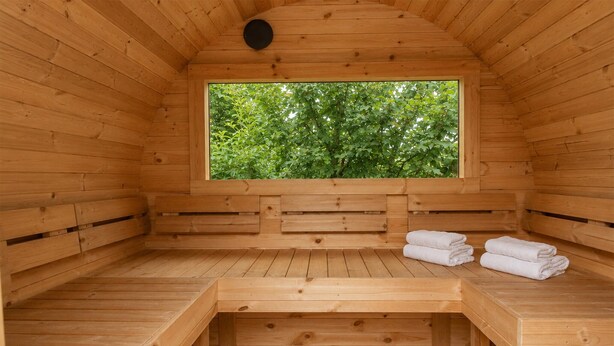 Una sauna de madera con bancos y una ventana que da a zonas verdes.