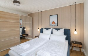 Un letto rifatto con lenzuola bianche, una testiera blu e un quadro appeso alla parete.