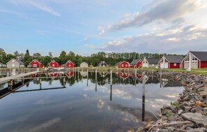 A calm waterfront with red buildings, a dock, and a clear sky.