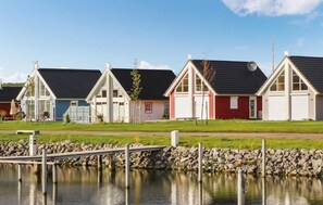 A row of colorful houses with a dock extending into a calm body of water.