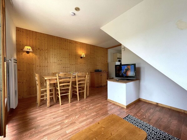 A compact living space with a wooden dining table and chairs, a small kitchenette, and a television on a stand. - Sunny Chalet 3 Rooms, 450m from Ski Lift, Free Wifi, Parking - Dévoluy (Le Dévoluy)