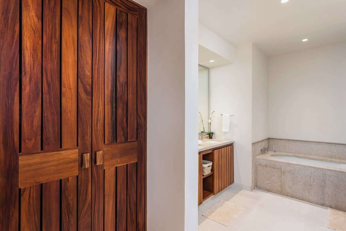 Un armario de madera en un baño con una bañera y un lavabo.
