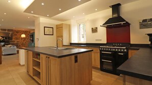 Una cocina moderna con una isla central, horno empotrado y campana extractora roja.