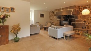 Una sala moderna con chimenea de piedra, sofás y un mueble de madera.