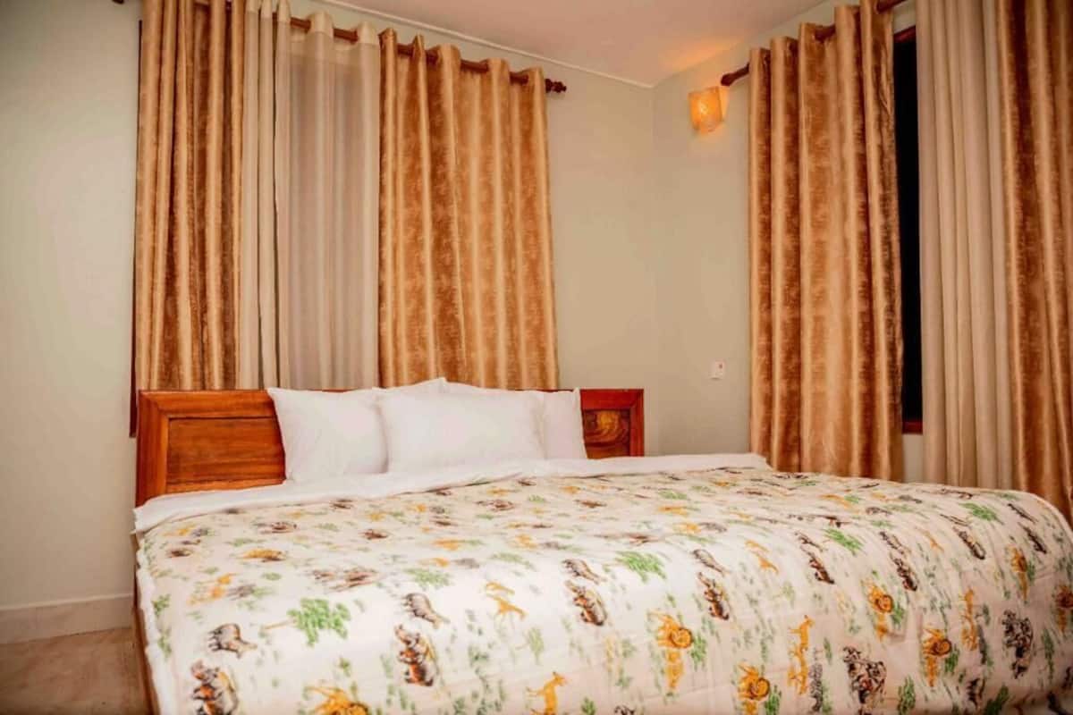 Un dormitorio con cama, cortinas y mesita de noche.