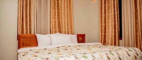 Un dormitorio con cama, cortinas y mesita de noche.