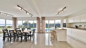Een moderne keuken met een groot kookeiland, een eetgedeelte met uitzicht op het zwembad en een uitzicht op de bergen.