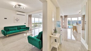 Een moderne woonkamer met een groene bank, een bijzettafeltje en uitzicht op het groen.