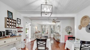 A spacious kitchen with white cabinetry, a dining area with a table and chairs, and a ceiling fan. - Hibiscus House Bed & Breakfast Inn Flamingo Suite (Fort Myers)