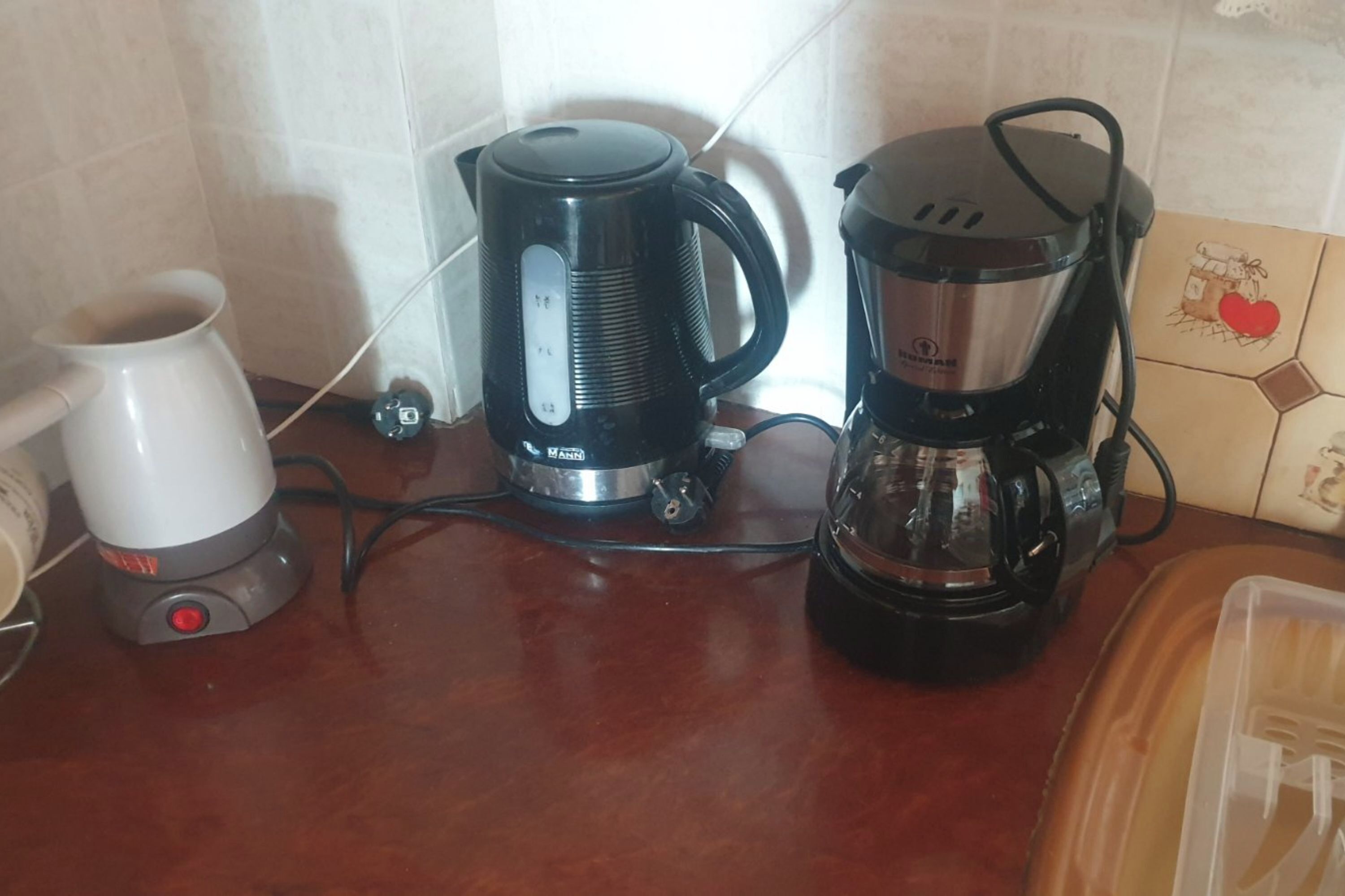 A kitchen counter with a coffee maker, a kettle, and a coffee pot.