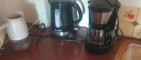 A kitchen counter with a coffee maker, a kettle, and a coffee pot.