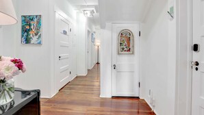Un pasillo con paredes blancas, suelo de madera y una puerta con un panel de vidrio decorativo.