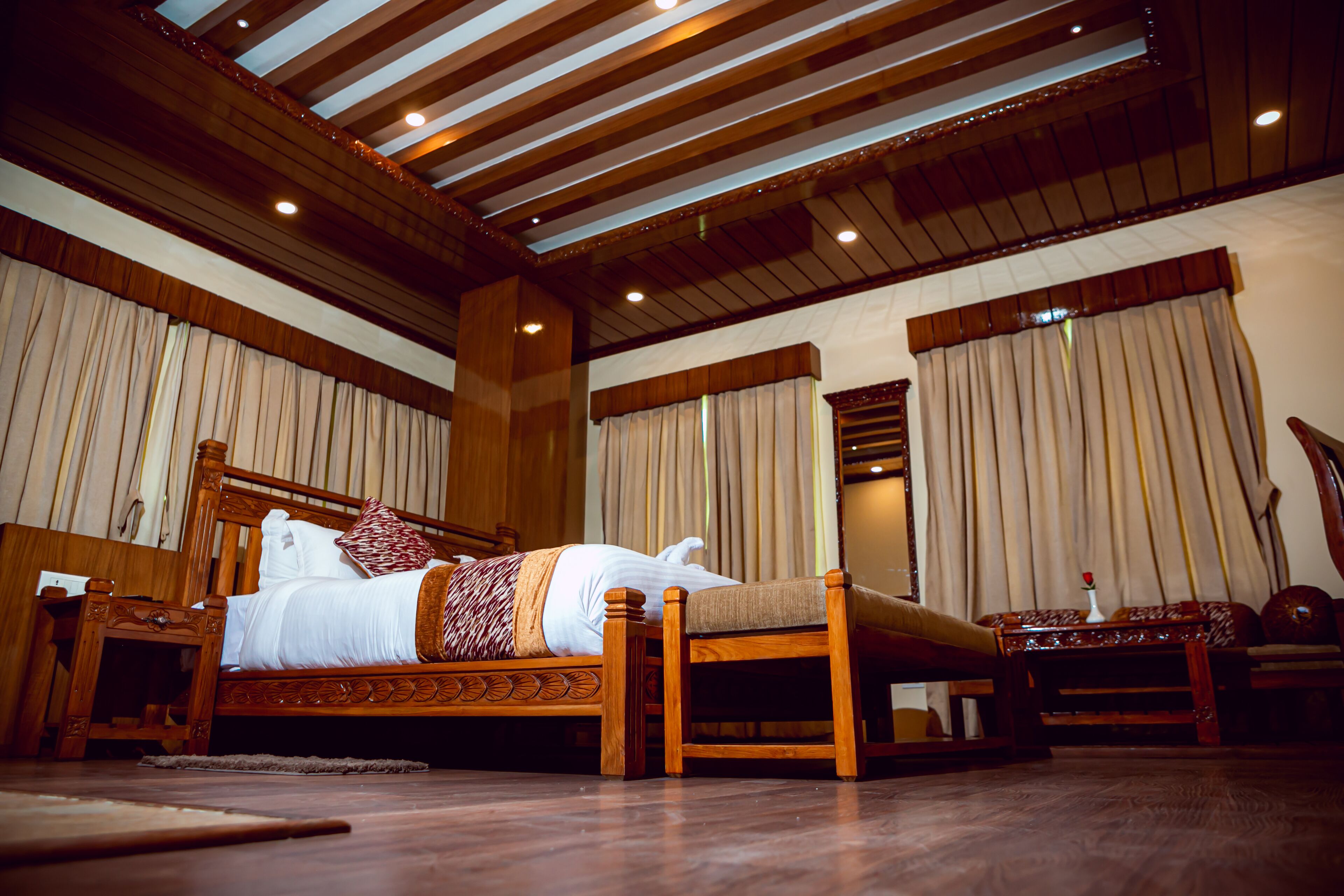 Un dormitorio amplio con una cama de madera, una mesita de noche y una silla de madera.
