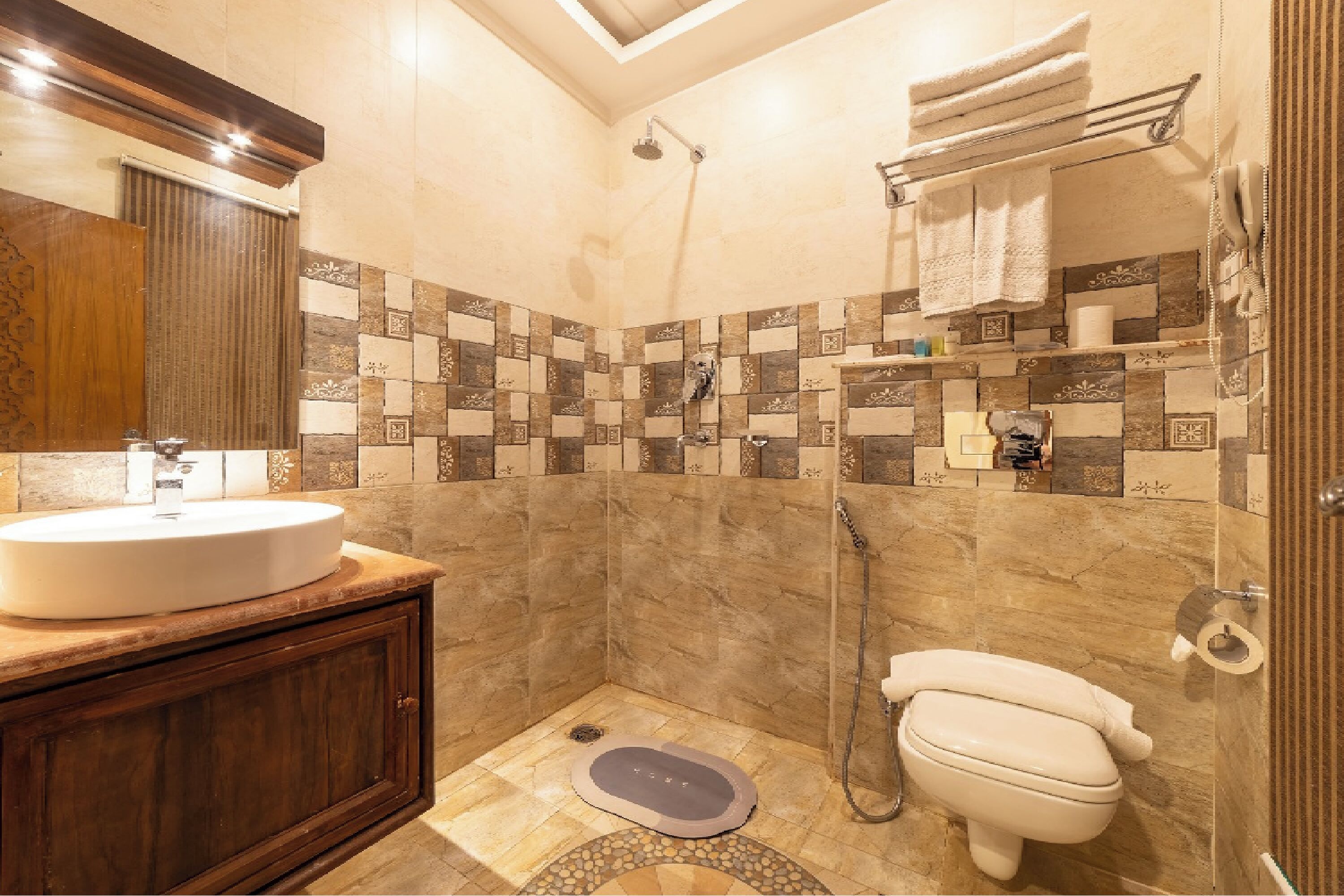 Un baño con lavabo, inodoro, ducha y pared de azulejos con diseño a cuadros.