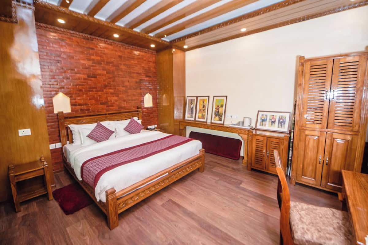 A bedroom with a wooden bed, a brick wall, a wooden wardrobe, and a bench.