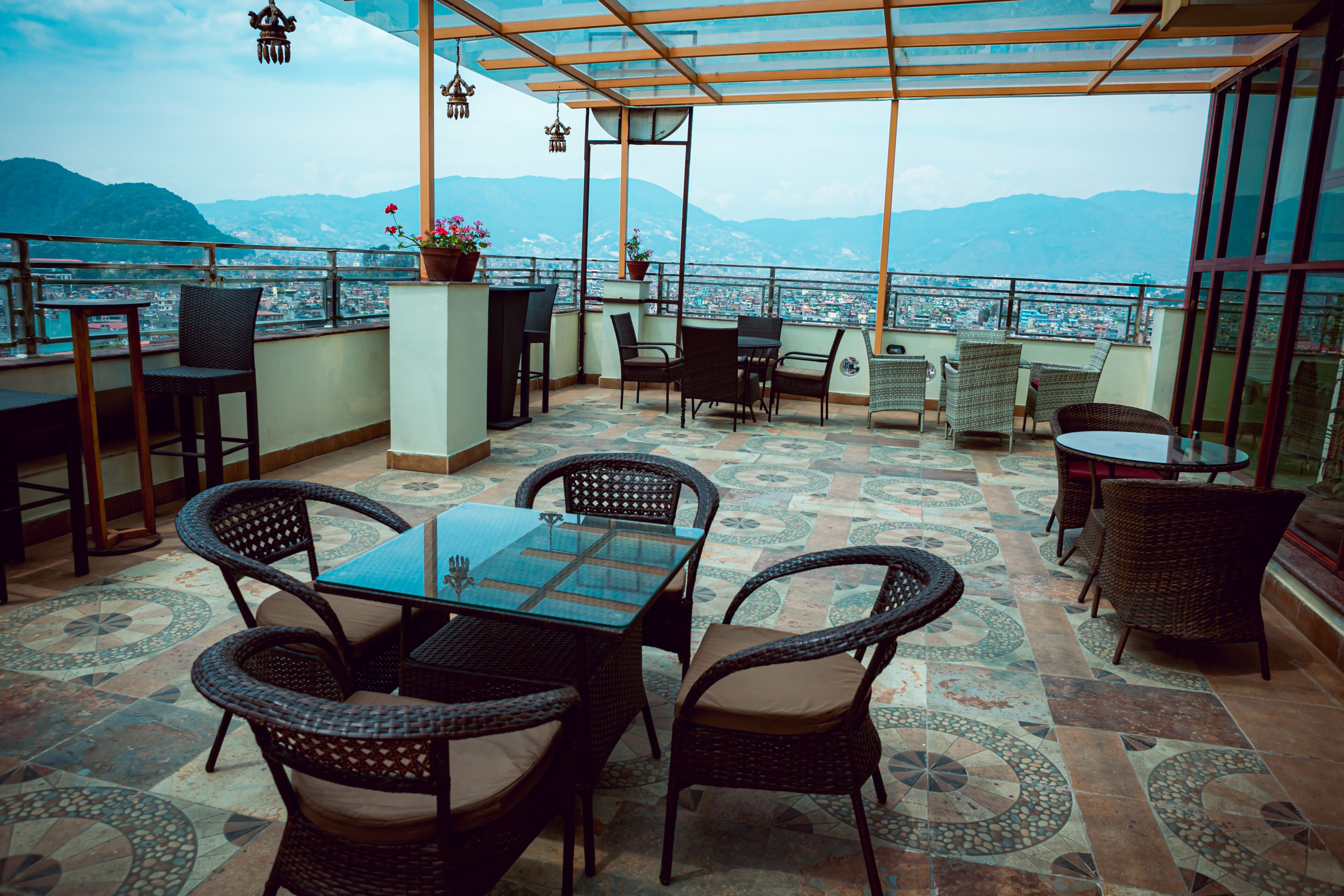 A terrace with wicker furniture, a glass table, and potted plants.