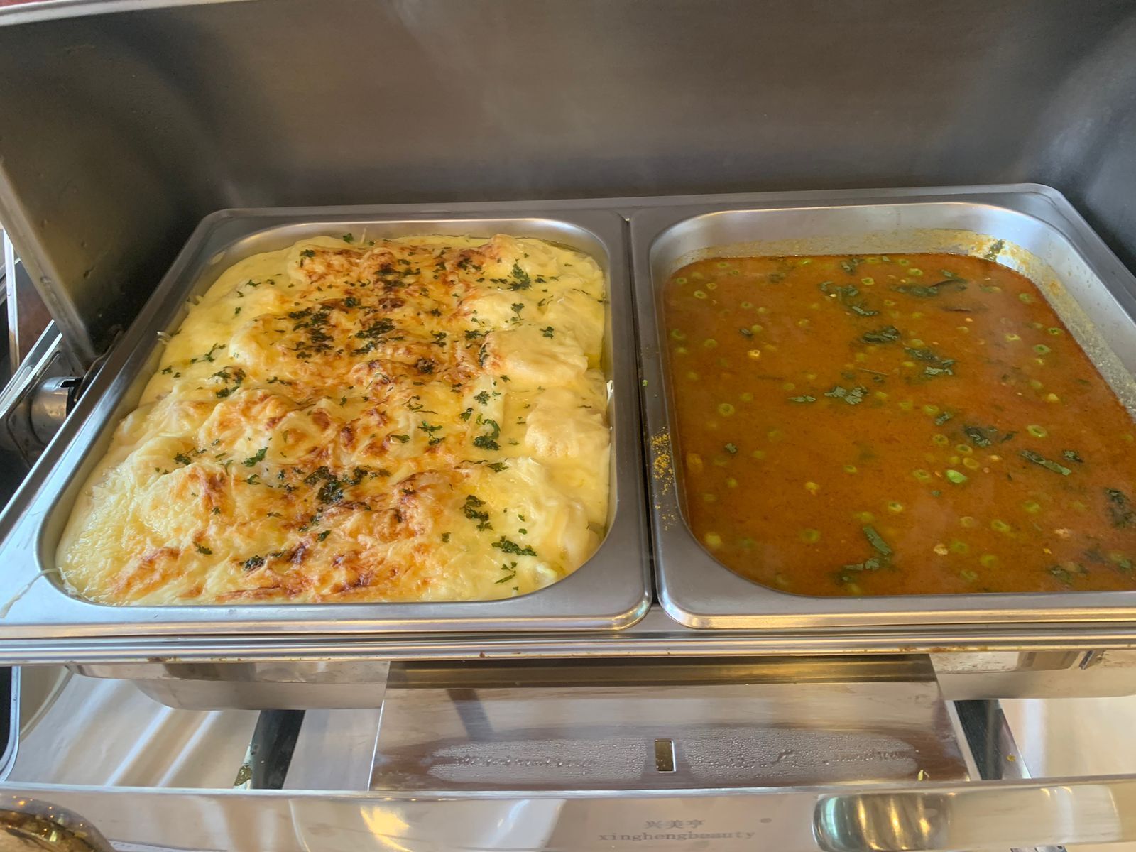 A buffet with two trays of food: one appears to be a baked casserole and the other a soup with vegetables.