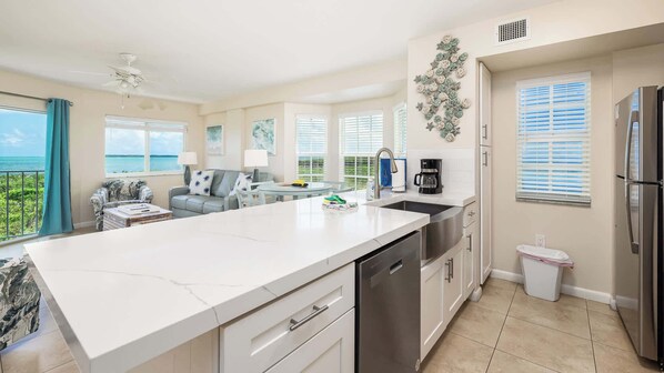 A modern kitchen with a large island, stainless steel appliances, and a view of the ocean. - Coral Penthouse | Corner Unit | Ocean Pointe 4216 (Tavernier)