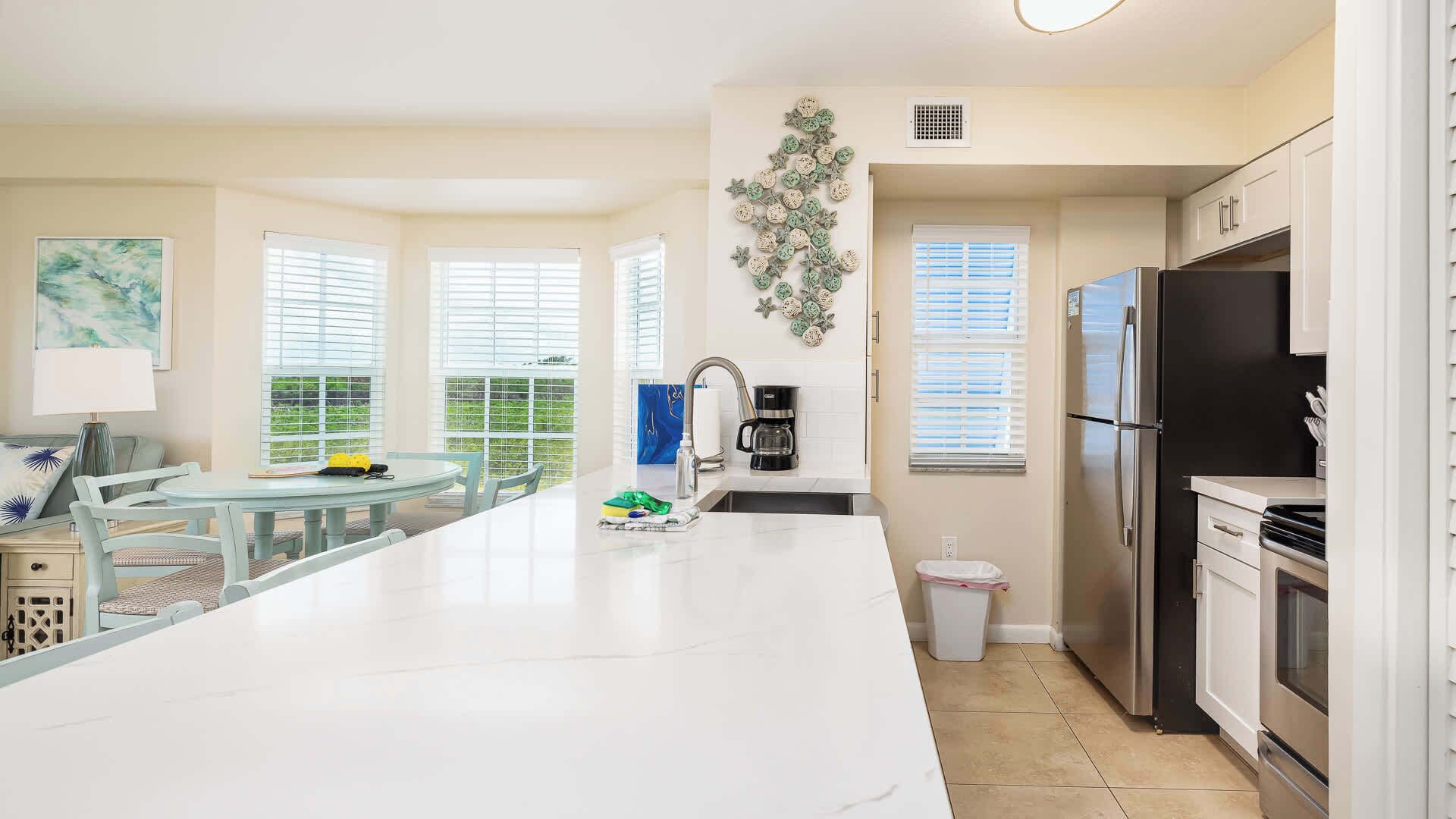 A modern kitchen with a central island, a dining area with a round table, and a refrigerator.