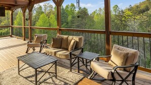 A wooden deck with outdoor furniture and a view of the forest. - Southern Smoke | Scenic Decks | Hot Tub | Wi-Fi (Rogers)
