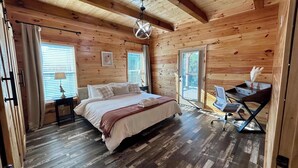 A wooden cabin bedroom with a bed, a desk, and a chair. - Southern Smoke | Scenic Decks | Hot Tub | Wi-Fi (Rogers)