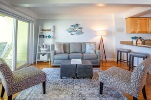 A living room with a grey sofa, patterned armchairs, a coffee table, and a floor lamp.
