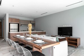 A modern kitchen with a dining area, a flat-screen TV, and a minimalist design.