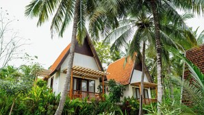 A two-story house with a tiled roof, surrounded by lush greenery and palm trees. - Green Coco Suite (Penida Island)
