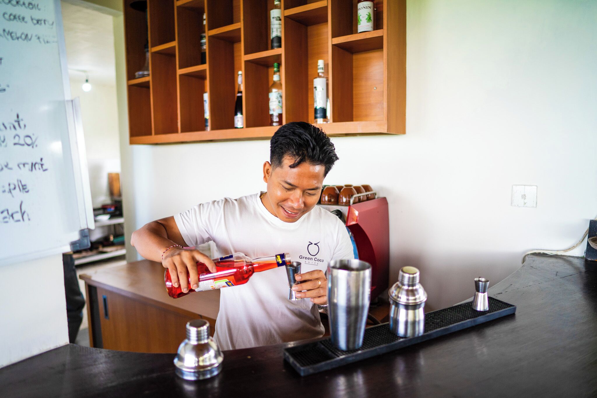 A bartender pouring a drink into a glass.