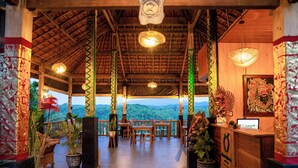 A restaurant with a wooden interior, tables, chairs, and potted plants. - Green Coco Suite (Penida Island)