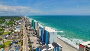 Un paisaje urbano costero con rascacielos, una playa y cielo despejado.