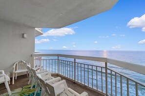 A balcony with white plastic chairs and a view of the ocean. - Garden City Beach Oceanfront Condo 911 | Rising Tides Properties (Murrells Inlet)