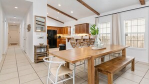 A spacious kitchen with wooden cabinets, a large wooden dining table, and a bench.