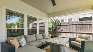 A covered patio with a sofa, a coffee table, and a cushioned chair.