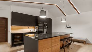 Een moderne keuken met een centraal eiland, inbouwapparatuur en een houten bank.