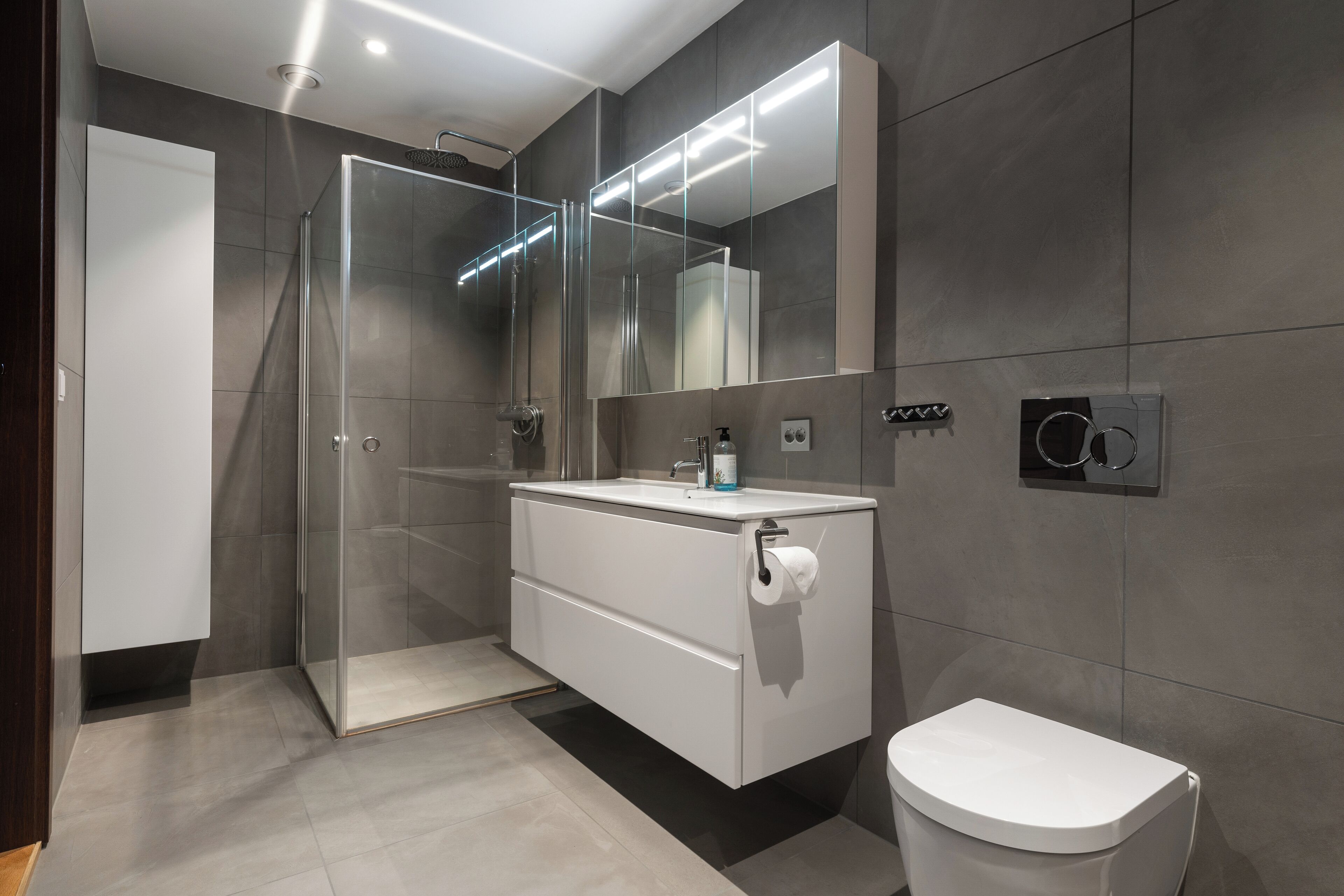 A modern bathroom with a glass-enclosed shower, a white vanity with a mirror, and a toilet.