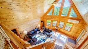 A wooden cabin with a loft bedroom, a living area with a fireplace, and large windows offering mountain views. - Adirondack Luxury Near Whiteface, Lake Placid (Jay)