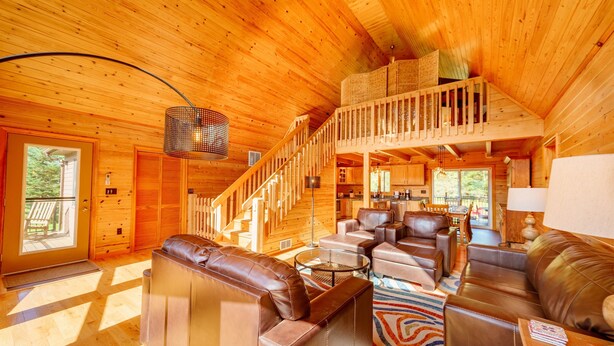 A wooden cabin interior with a staircase leading to a loft, leather furniture, and a dining area. - Adirondack Luxury Near Whiteface, Lake Placid (Jay)
