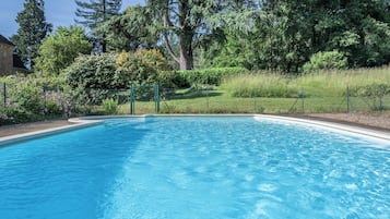 A clear blue swimming pool surrounded by lush greenery and trees.