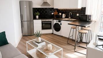 Eine moderne Küche mit Kühlschrank, Backofen, Mikrowelle und Waschmaschine.