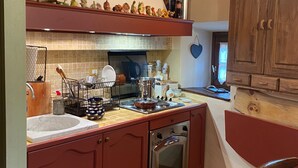 A kitchen with red cabinets, a wooden ceiling, and a tiled backsplash. - Cozy and small apartment in the heart of vauban - briancon (Briançon)