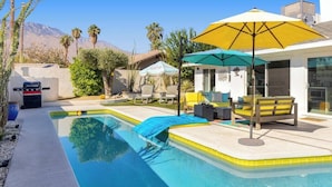 A pool area with a barbecue grill, outdoor seating, and umbrellas. - Amarillo House - Luxury Home With Pool Spa (Palm Springs)