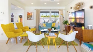 A modern living room with a sofa, yellow chairs, a coffee table, and a TV. - Amarillo House - Luxury Home With Pool Spa (Palm Springs)