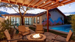 An outdoor patio with wicker chairs, a fire pit, and a swimming pool. - Poolside Palm Springs Paradise (Palm Springs)