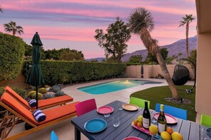 Relax by the serene pool surrounded by lush greenery and palm trees, perfect for social gatherings and relaxation.